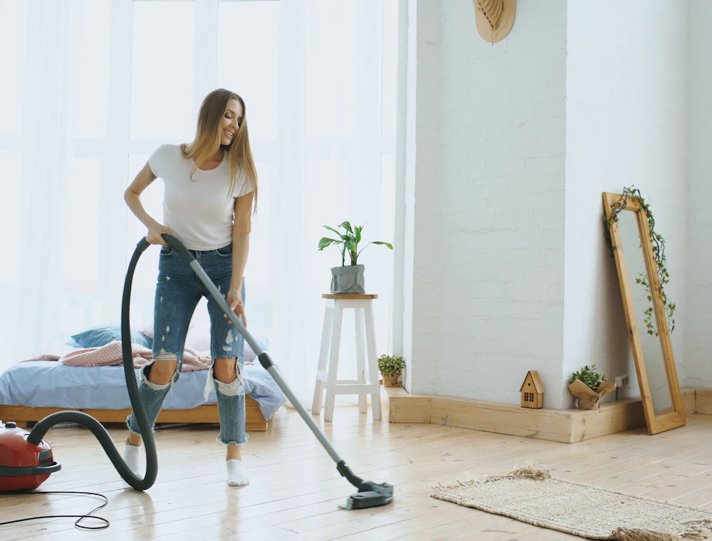 Cleaner vacuuming a bright bedroom